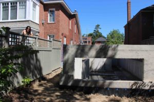photo of monica alongside fence next to new foundation walls after backfill completed