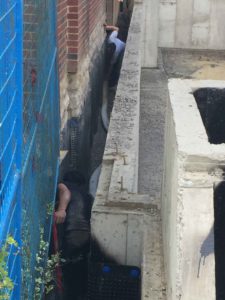 photo of men positioning weeping tile between foundation walls of new house and neighbour's house